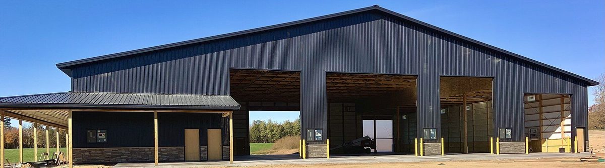 Dark open-front post-frame building with a metal roof